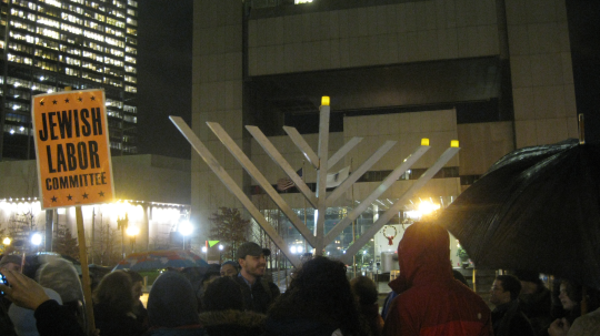 The Jewish Labor Committee and friends Occupy Hanukkah and the Holidays at Dewey Square Boston. The Federal Reserve Bank of Boston is in the background.